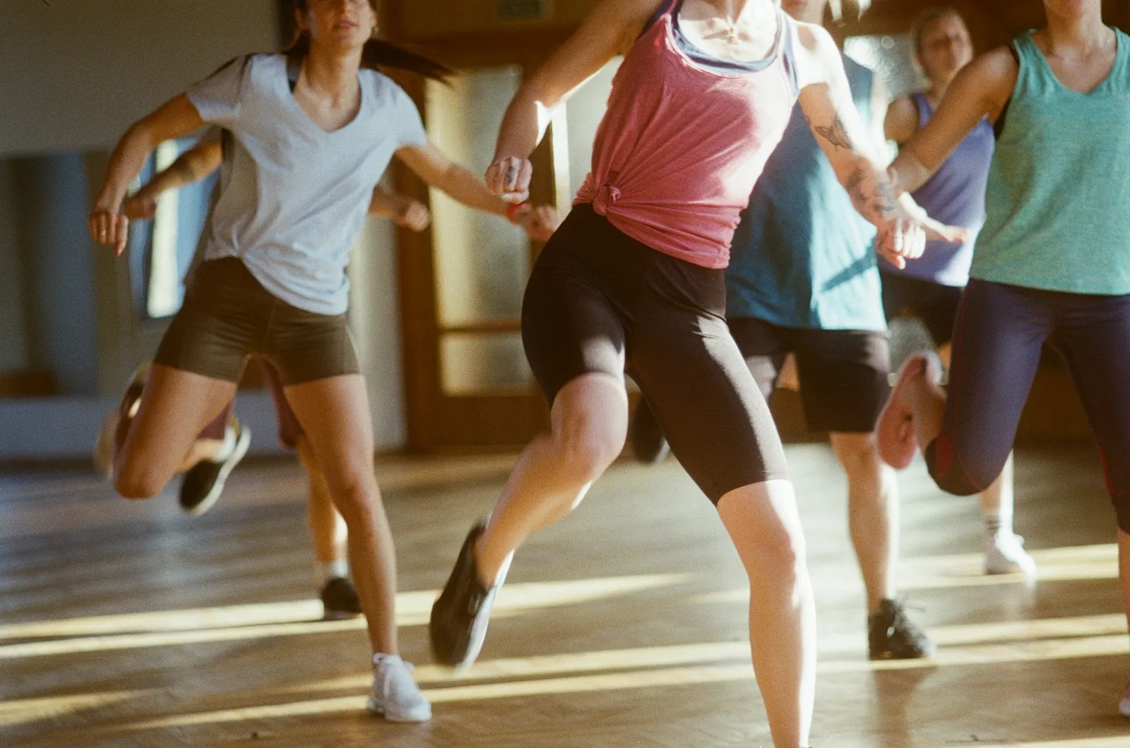 Group fitness class doing lunges together in a sunlit studio