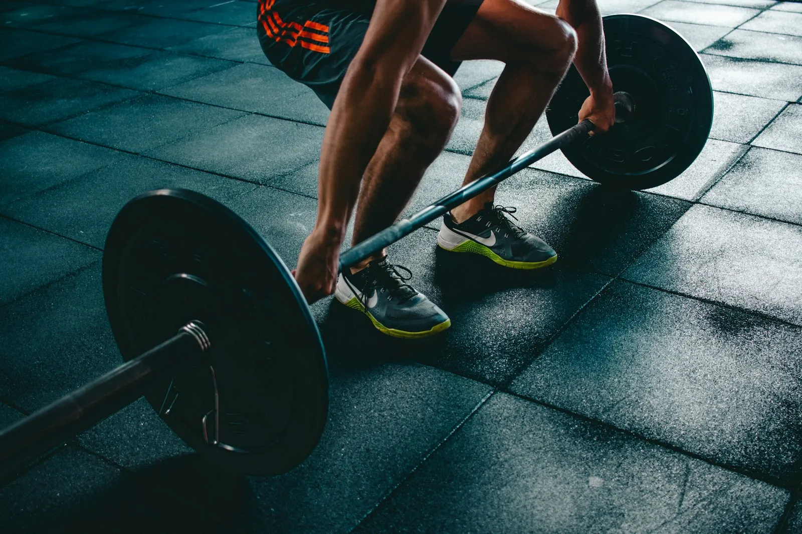 Athlete setting up a barbell deadlift on a rubber gym floor