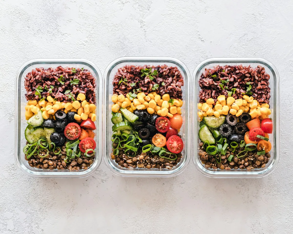 Three meal-prep containers with grains, chickpeas and vegetables