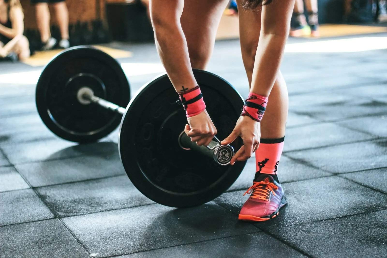 Athlete loading a weight plate onto a barbell on a gym floor