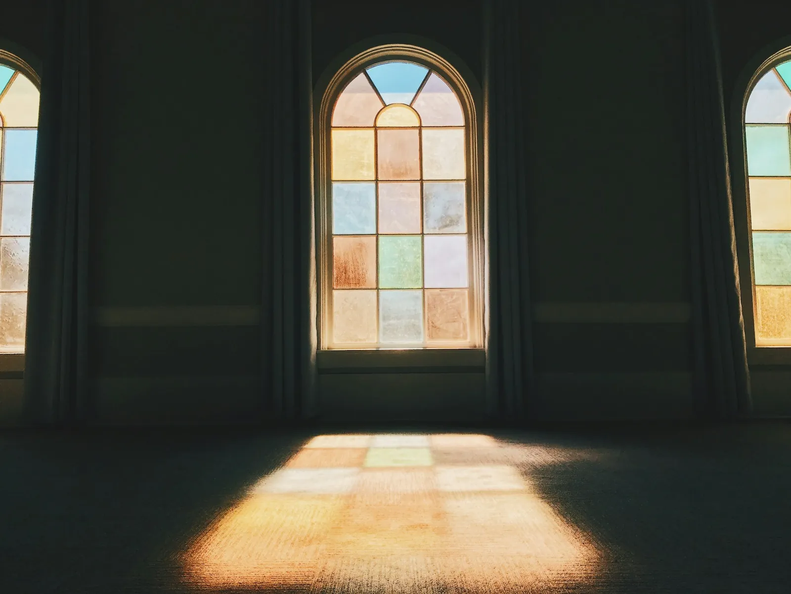 Morning light from arched windows falling across a chapel floor