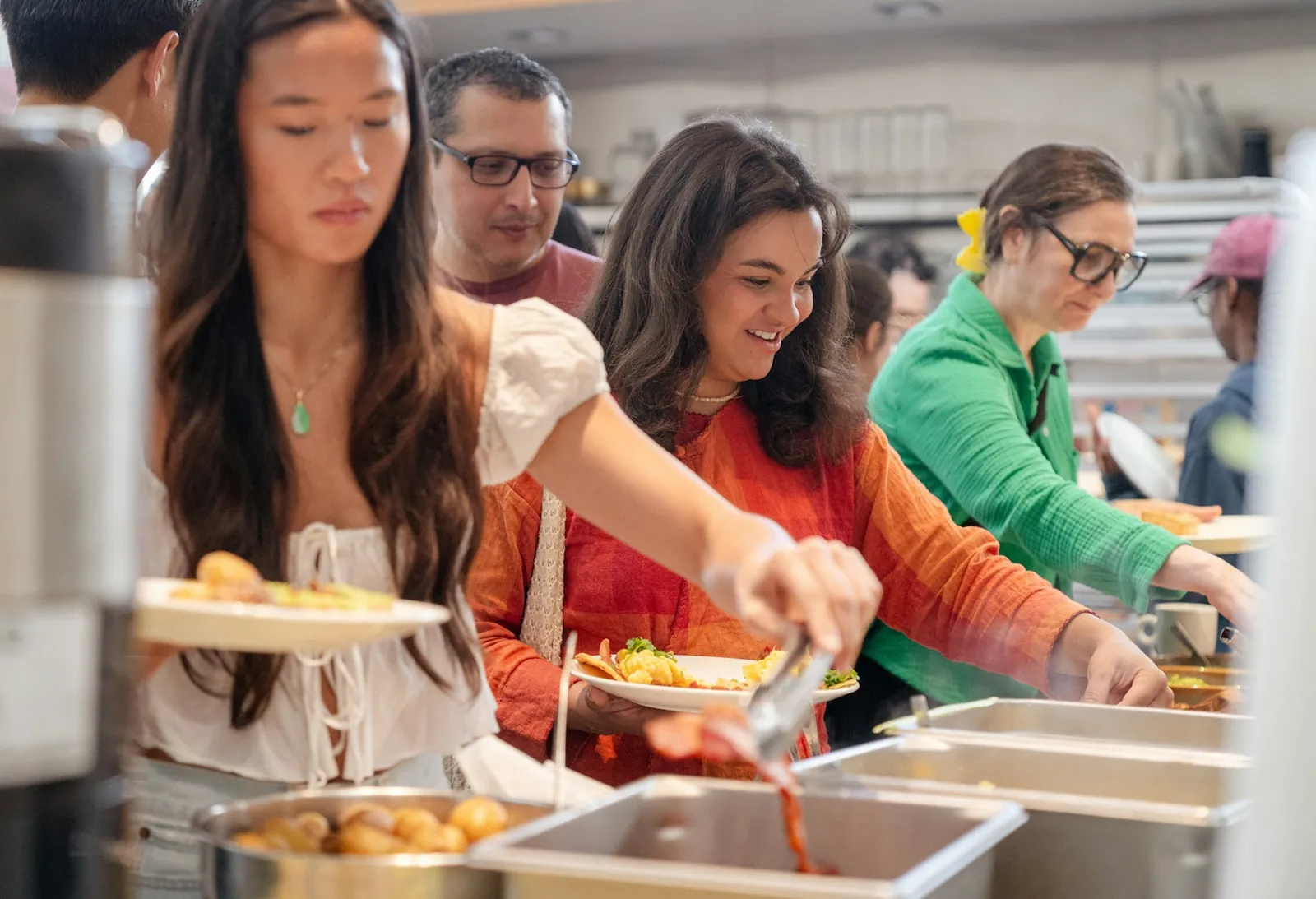 Volunteers serving food along a buffet line