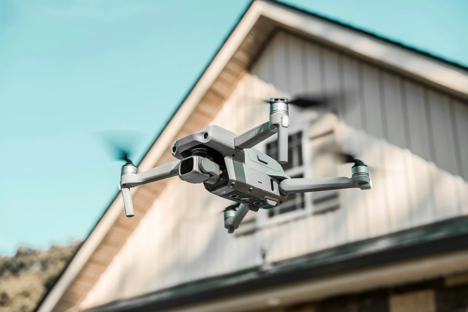 A drone hovering beside the gable of a house