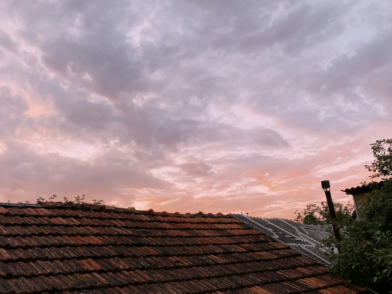 Clay tile roof under a pink and purple sunset sky