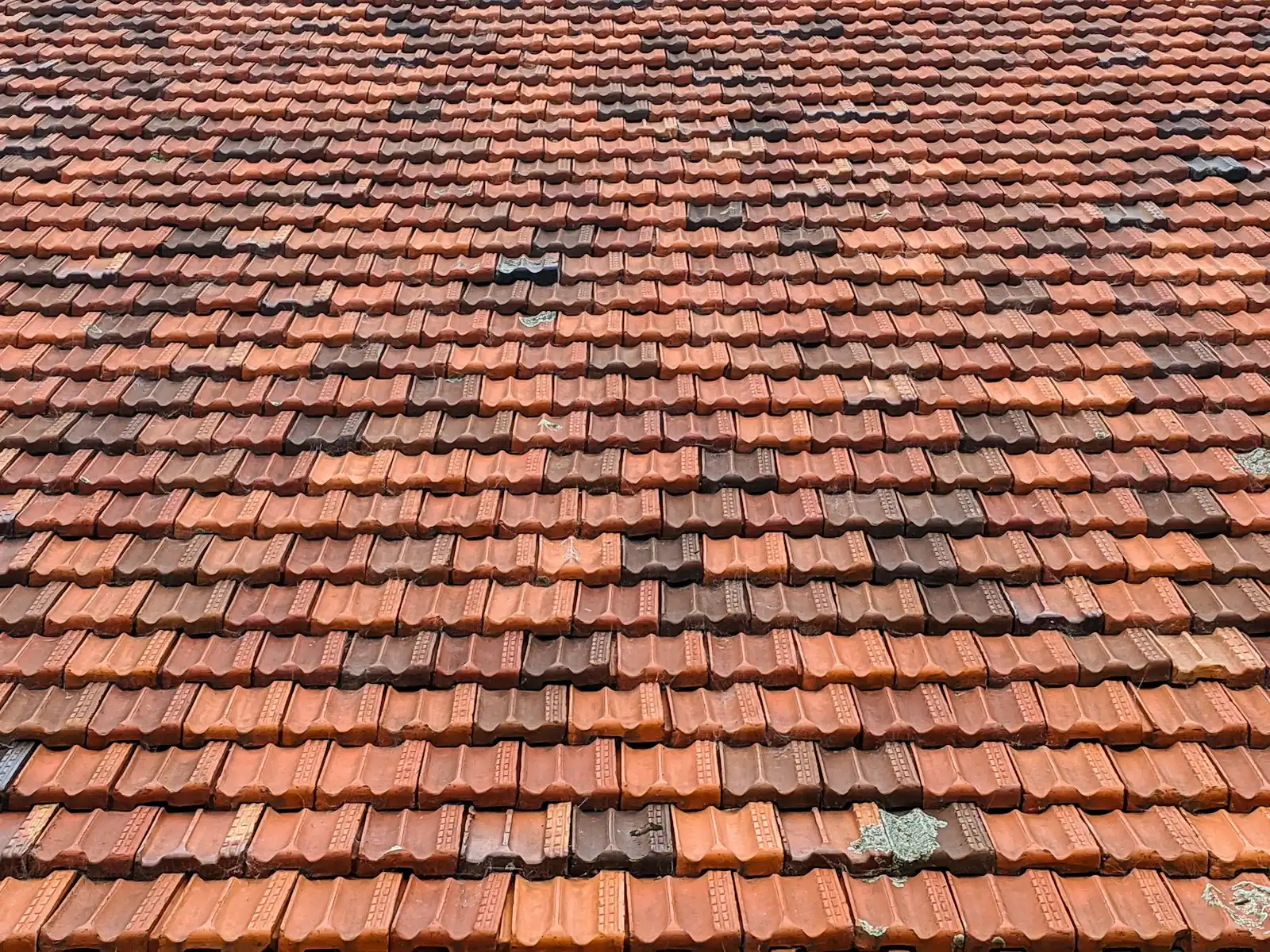 Before: weathered tile roof with faded and patched tiles