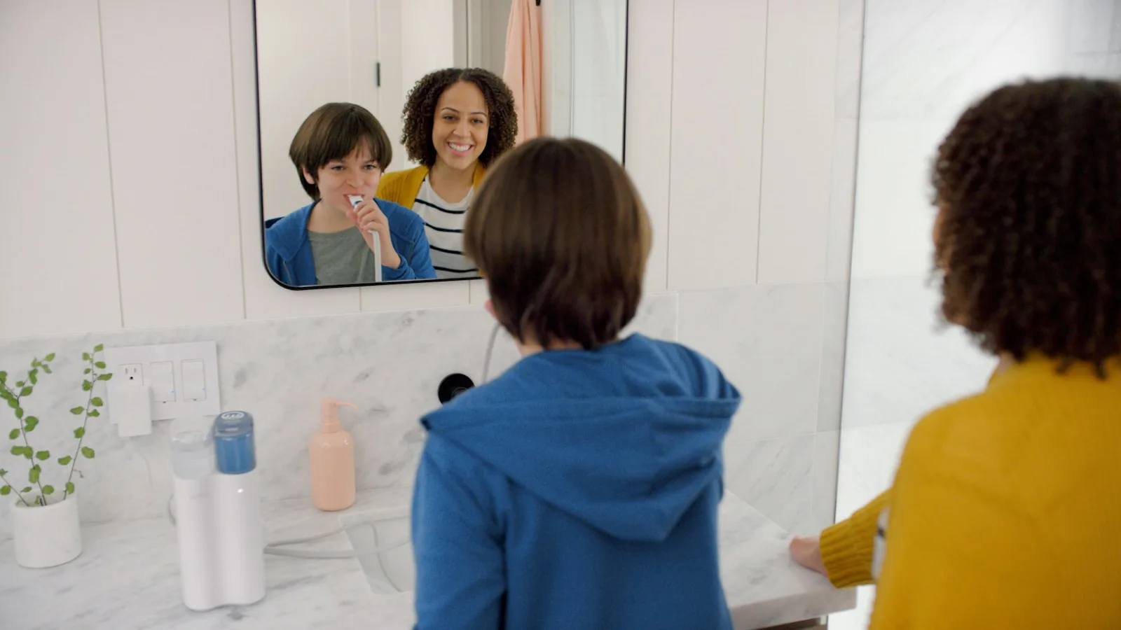 Parent and two kids brushing teeth together at a bathroom mirror