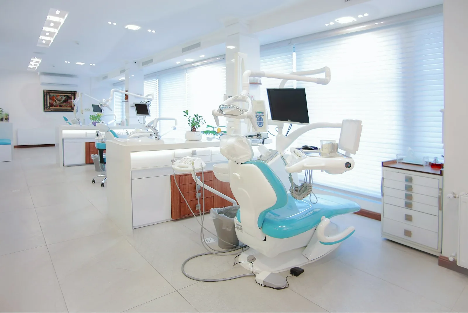 Bright, airy dental treatment room with a teal chair and large windows