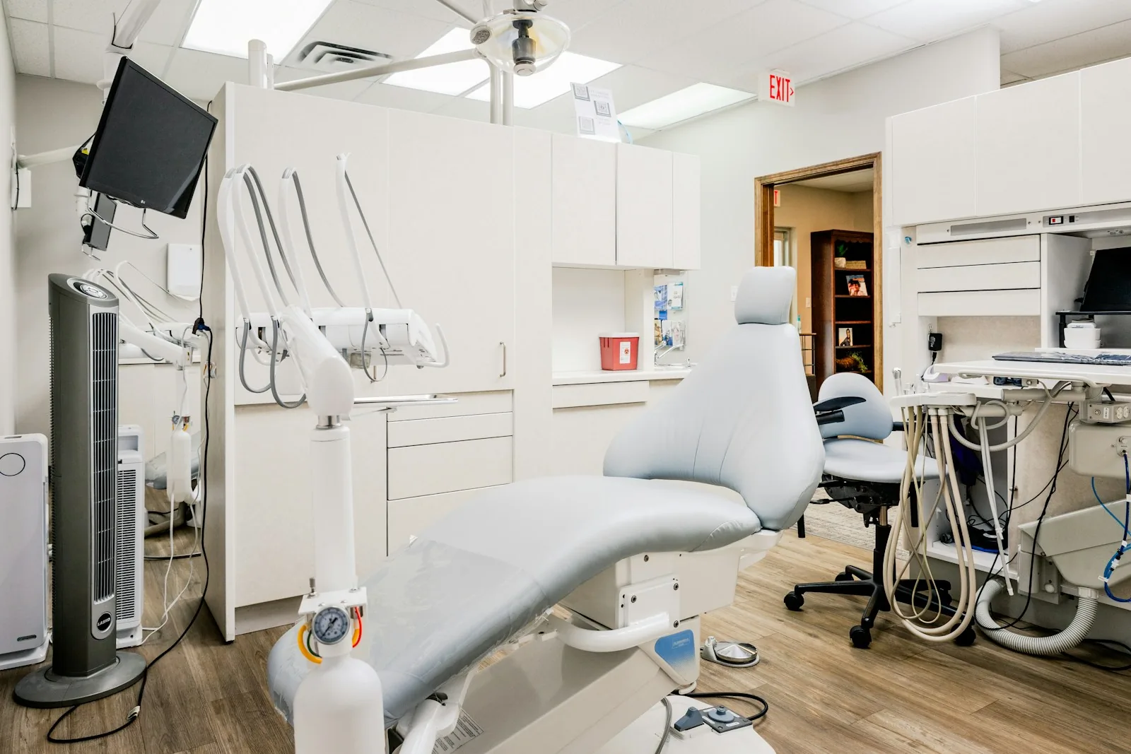 Calm dental operatory with a pale gray chair and wood floor