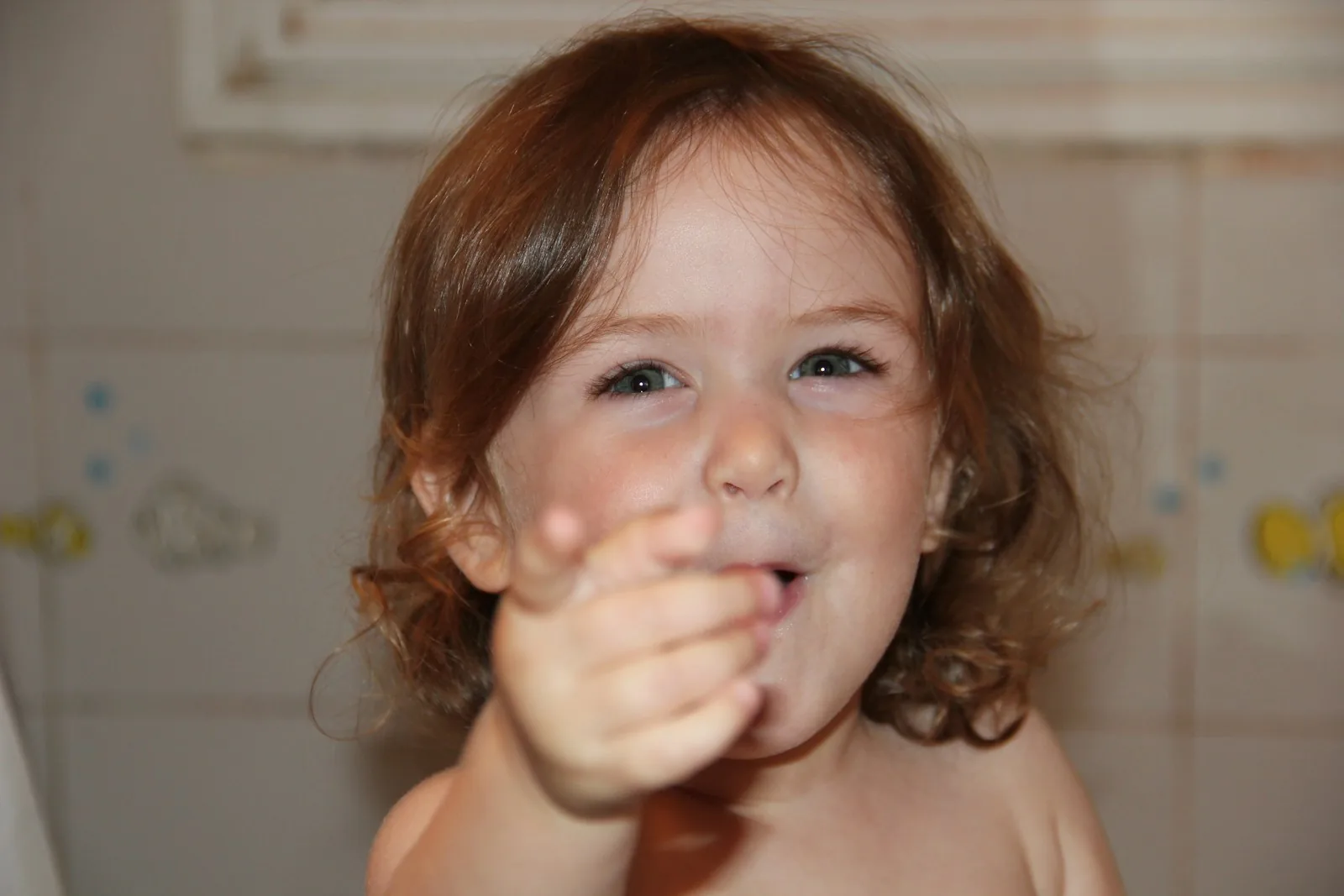 Toddler grinning while brushing teeth
