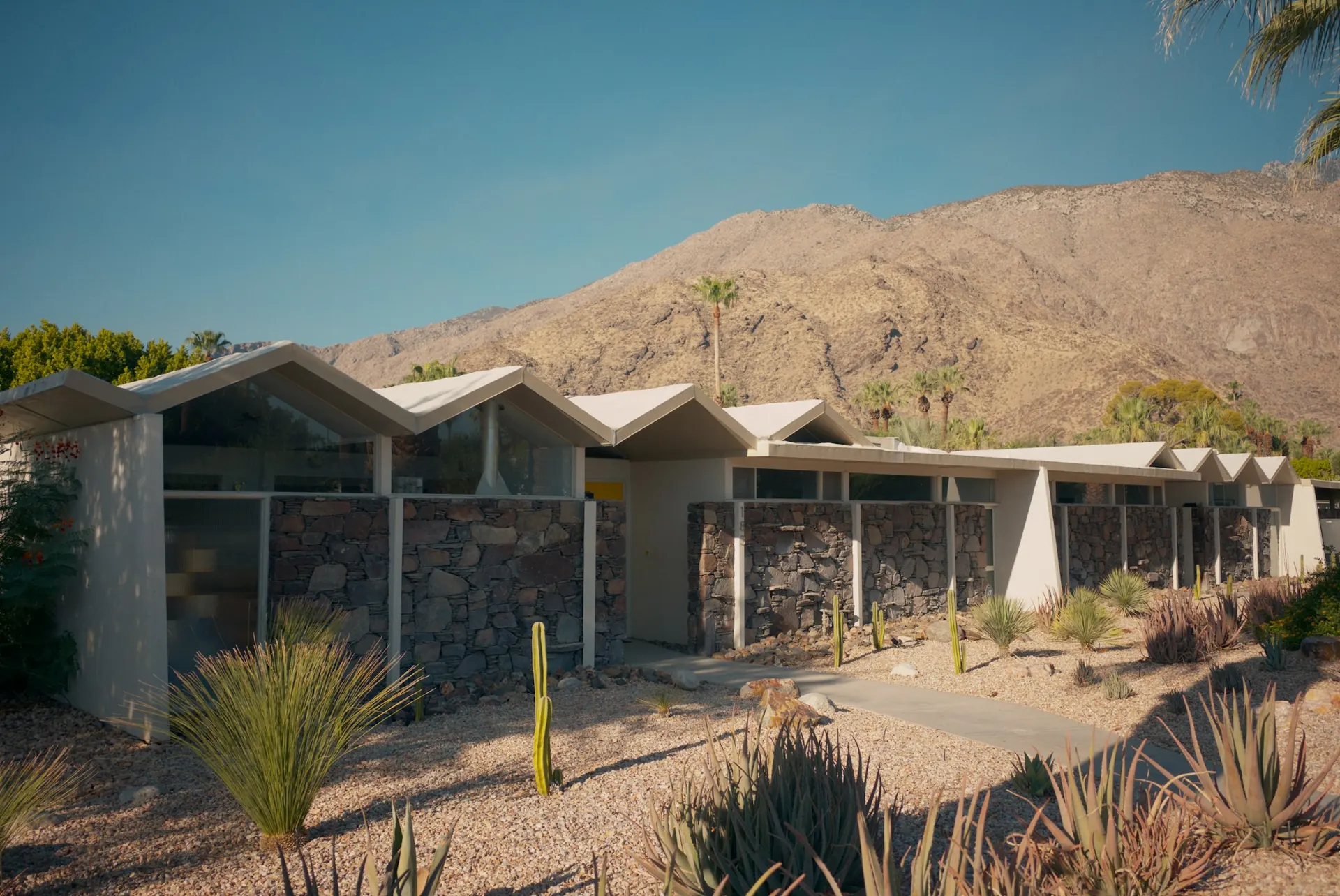 Mid-century desert home with gabled roofline below a dry mountain ridge