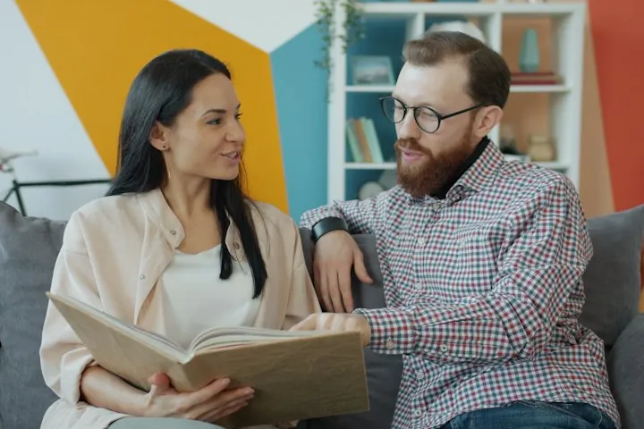 Couple on a couch looking through a family photo album