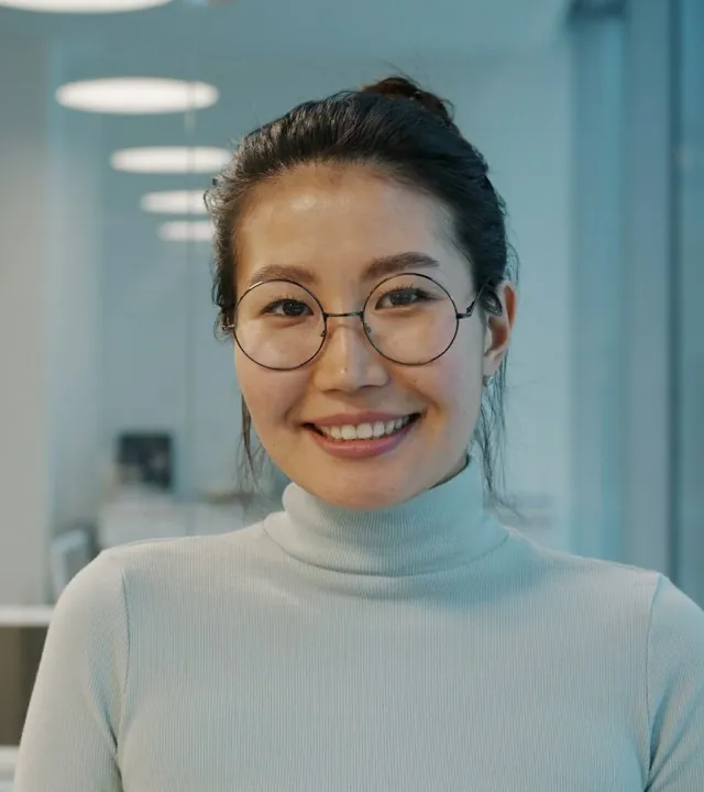 Portrait of Mei Tanaka, a smiling agent with glasses