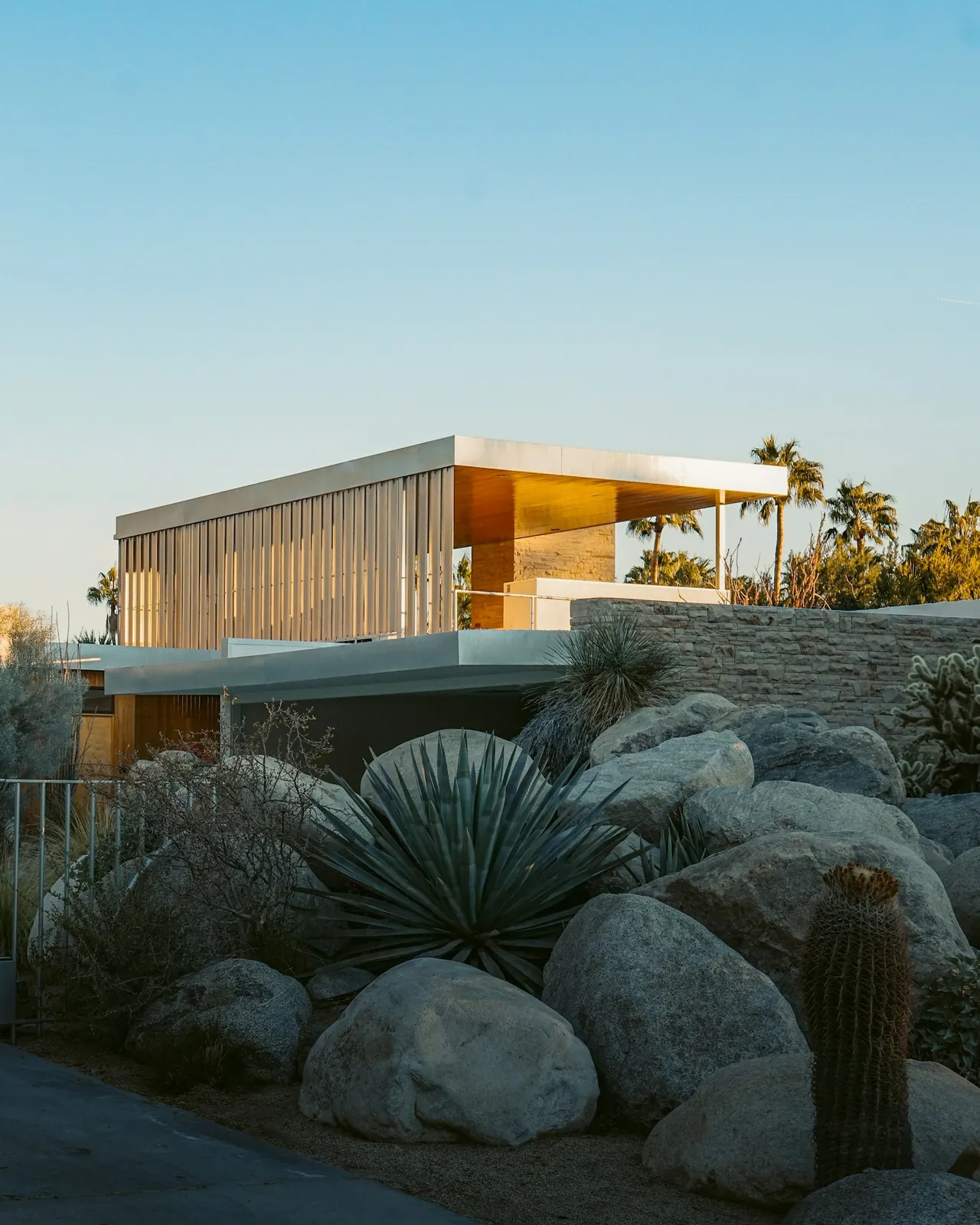 Modern desert home above a slope of boulders and blue agaves
