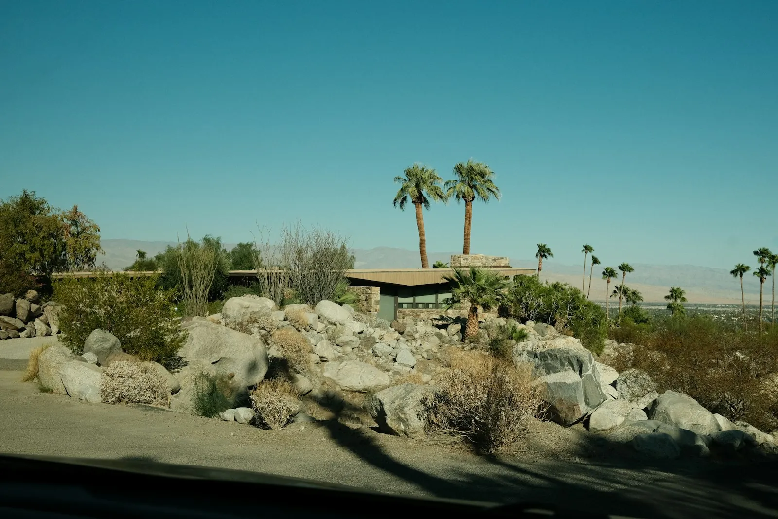 Low desert home with a boulder-and-gravel yard and palms