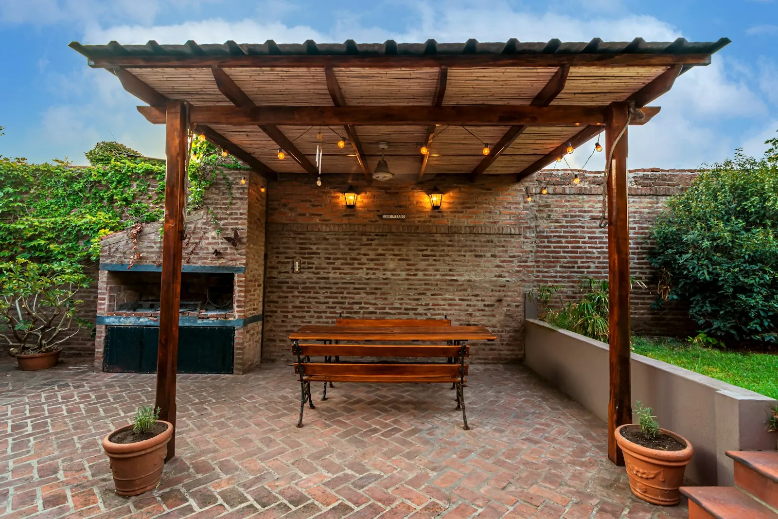 Wood pergola over a brick paver patio with an outdoor grill