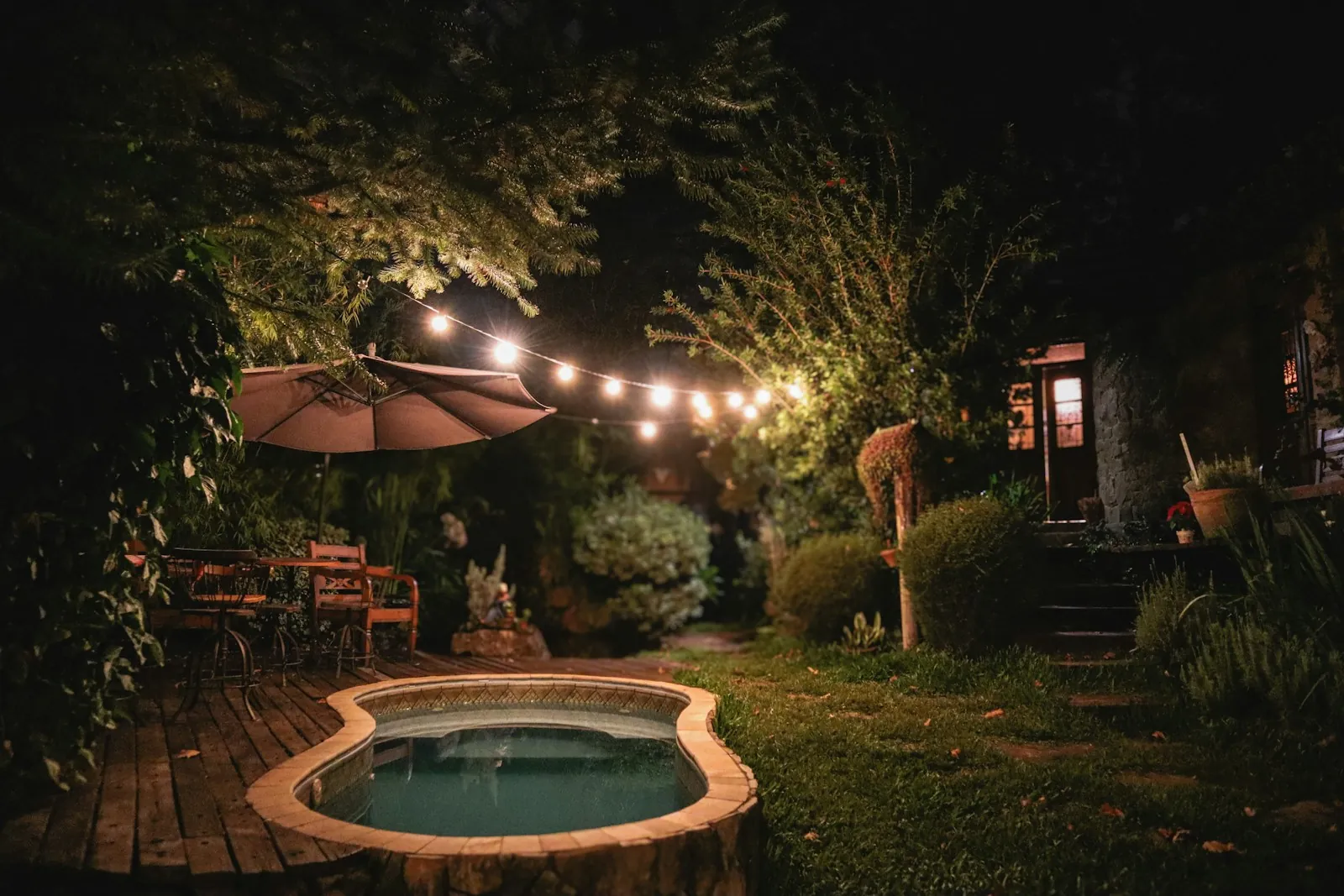 Backyard spa glowing under string lights at night