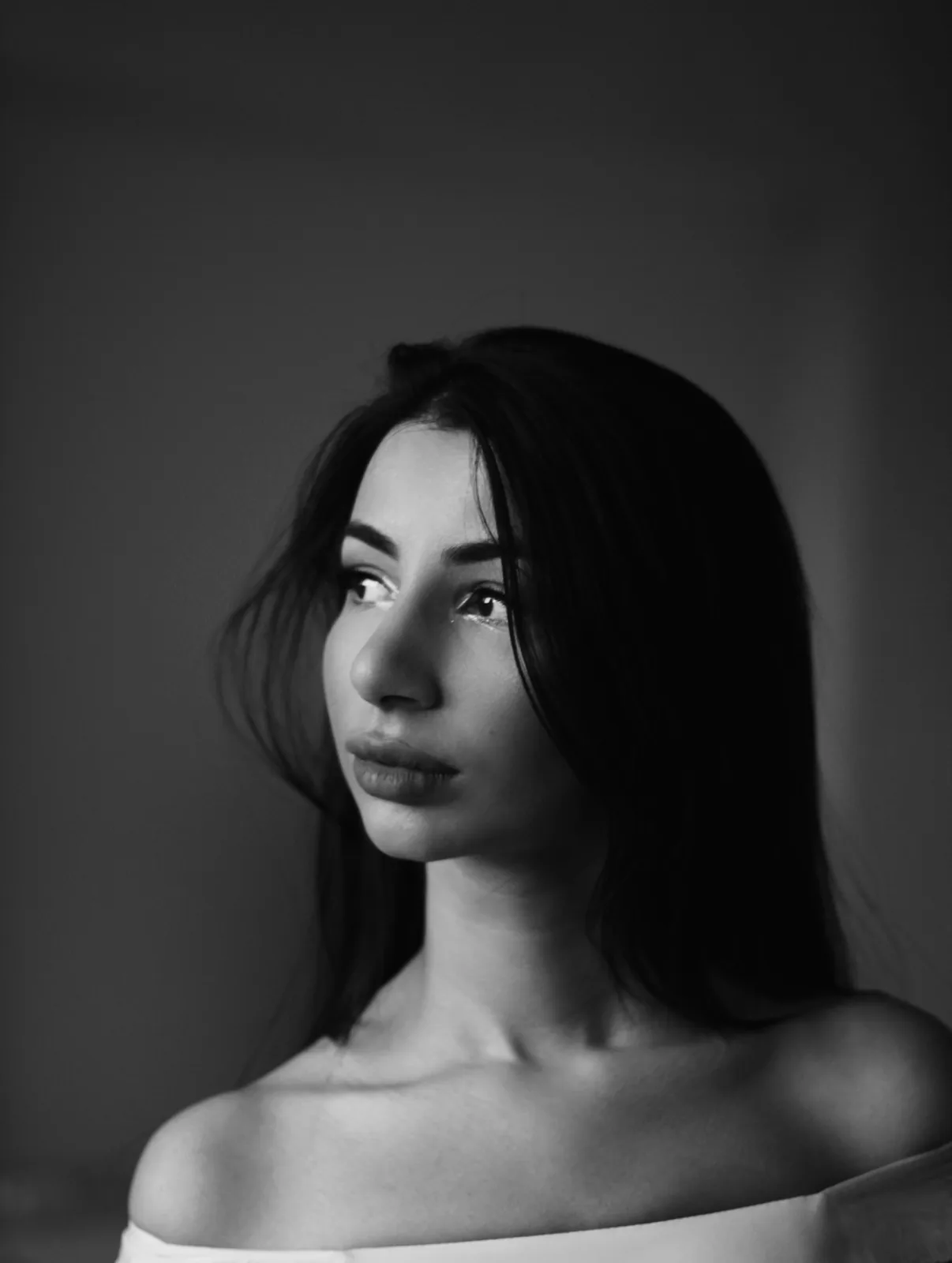 Black-and-white portrait of a woman glancing over a bare shoulder (stock photo, model)