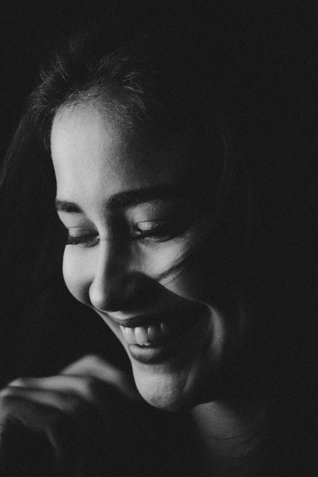 Black-and-white portrait of a woman smiling softly with eyes lowered