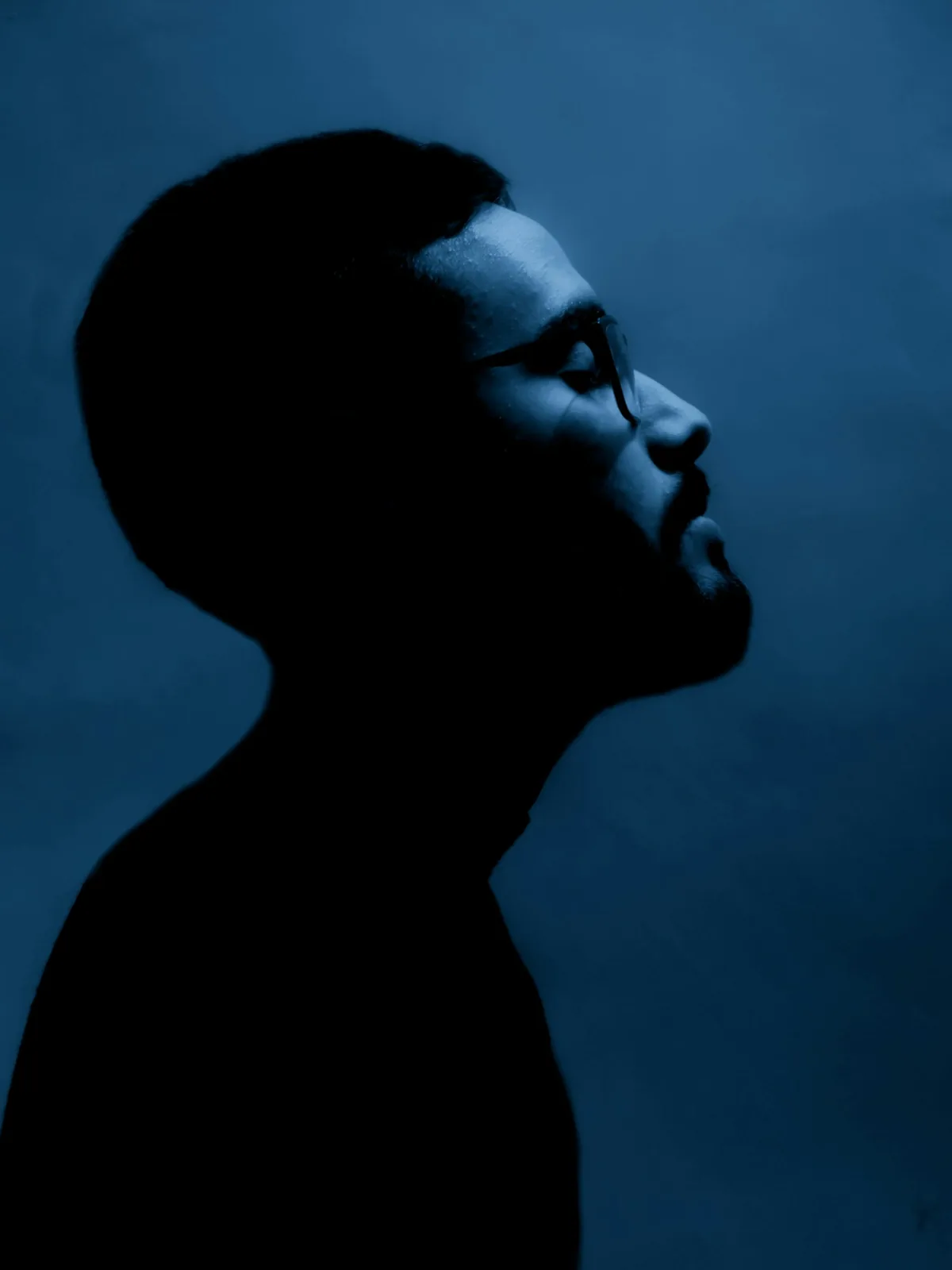 Man in profile against a deep blue backdrop