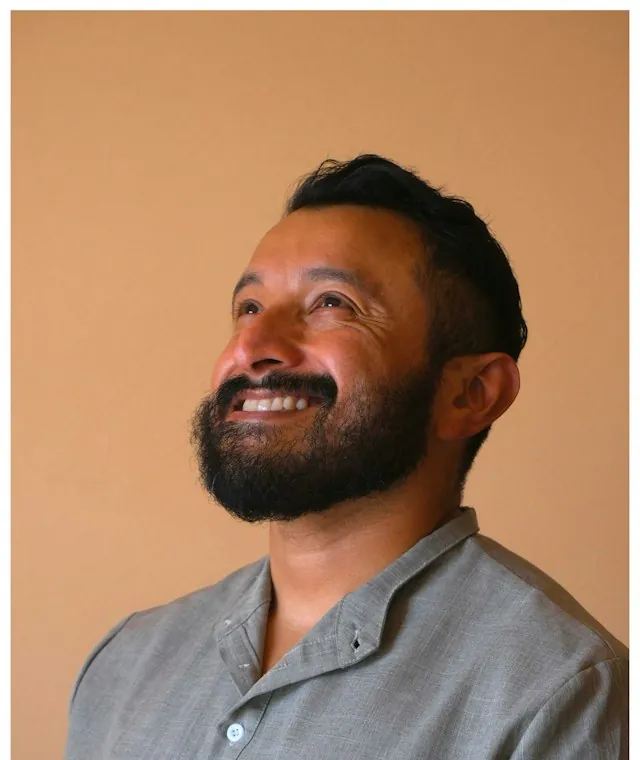 Bearded man smiling against a warm tan background