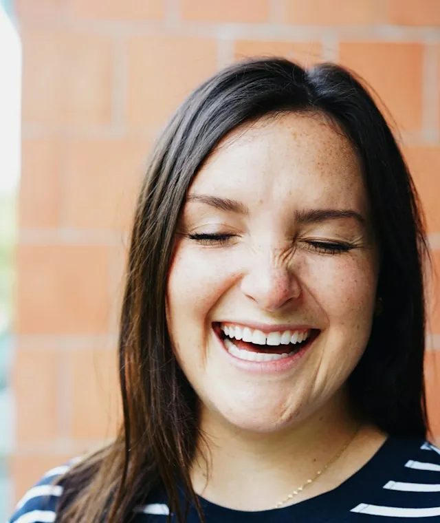 Laughing woman in a navy-and-white striped shirt