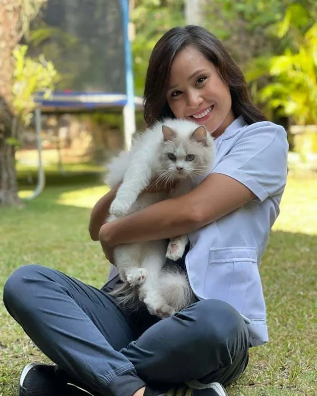 Smiling pet care professional holding a long-haired white cat