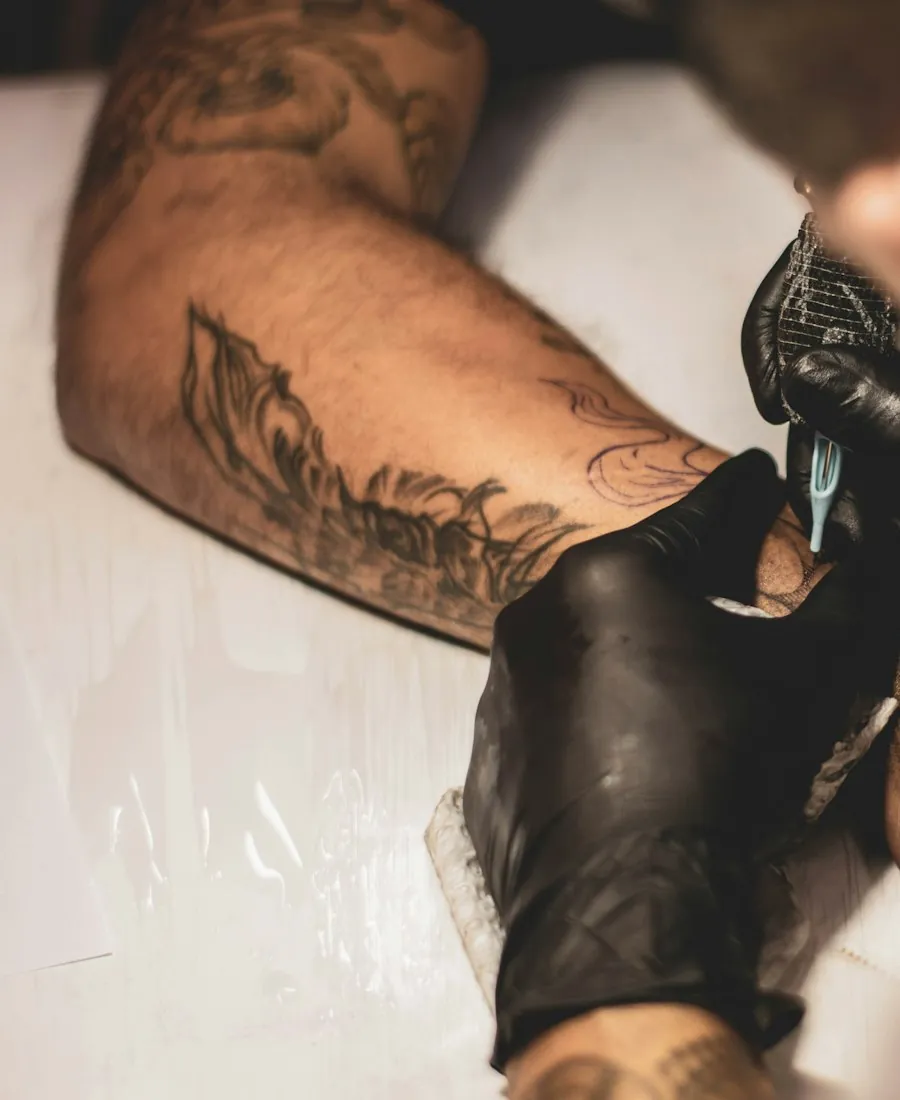 Close-up of a gloved hand tattooing a forearm