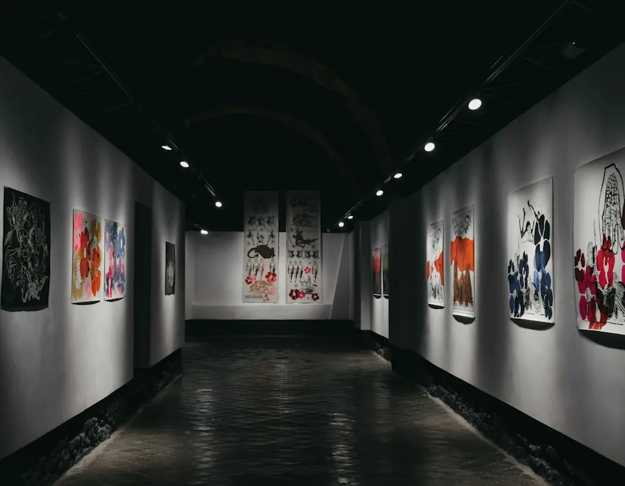 Long dark gallery corridor with lit prints on both walls