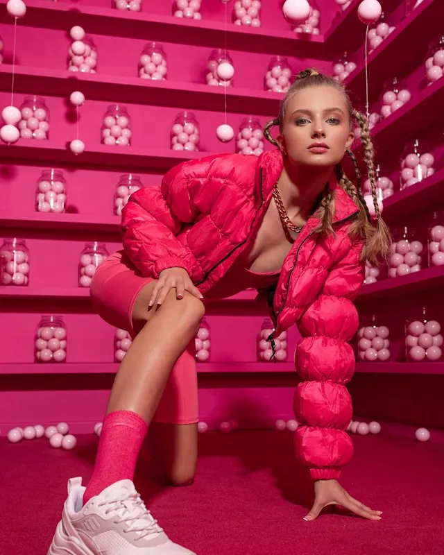 Hot pink cropped puffer jacket with pink chunky sneakers in a pink room